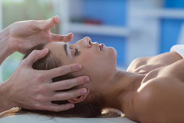 male physiotherapist giving head massage to female patient in clinic