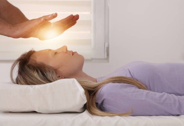 reiki healer doing holistic treatment to young woman. energy chakra balancing